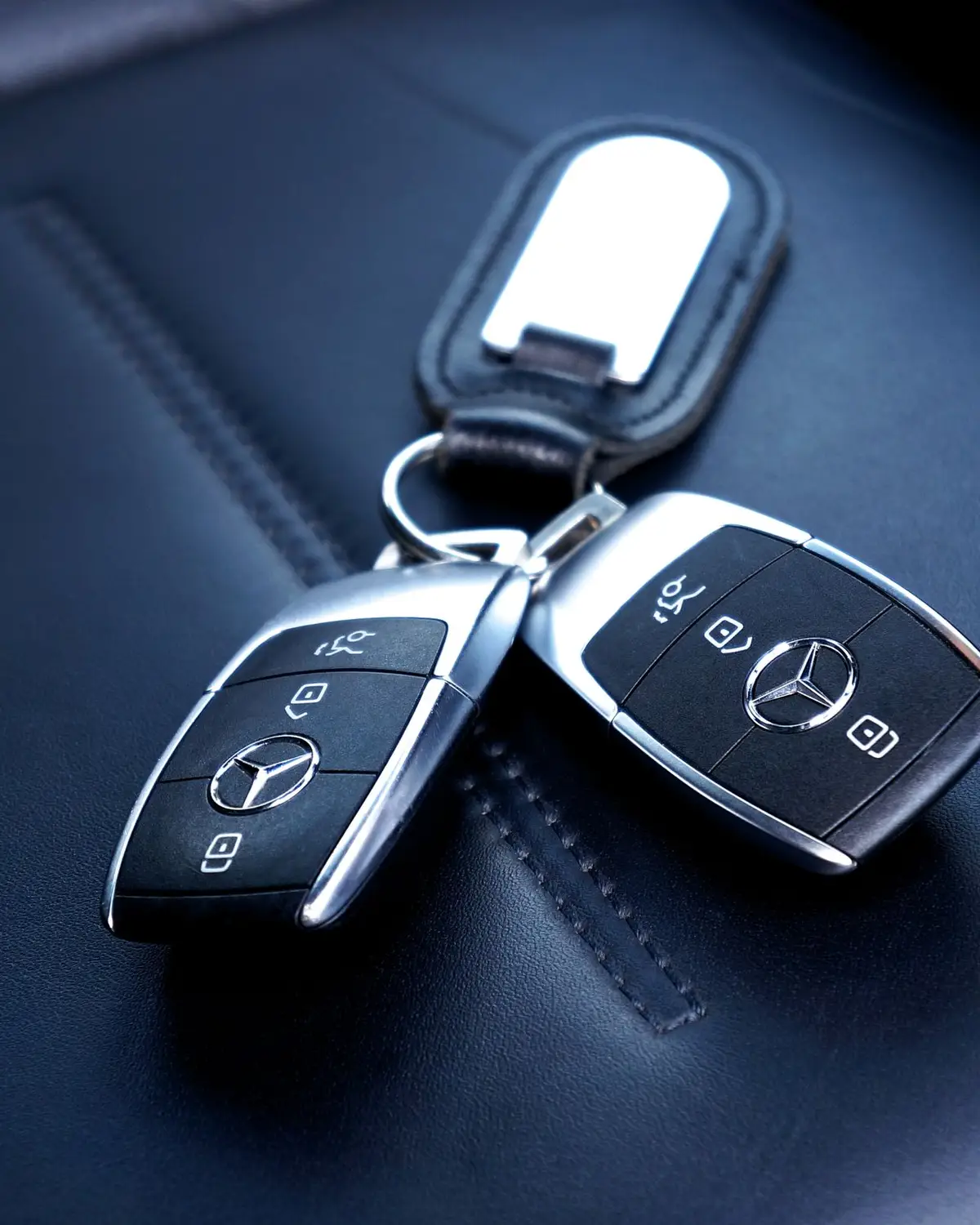 Two smart car keys resting on dark leather