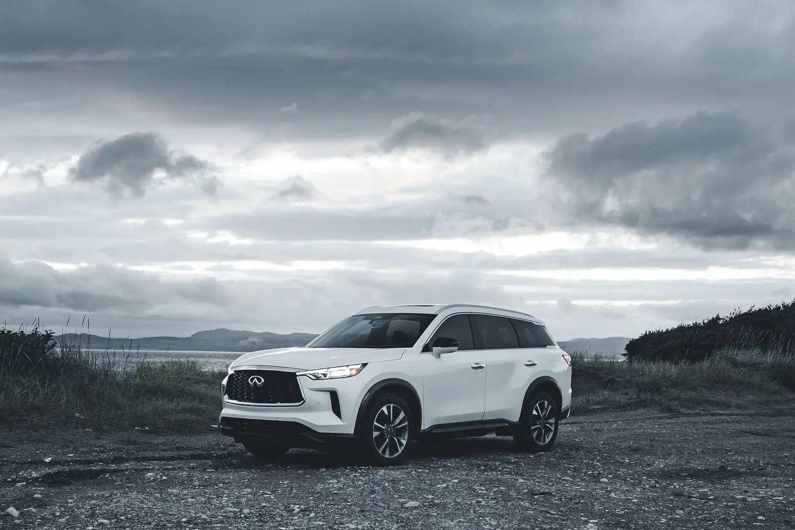White SUV parked on gravel under a cloudy sky