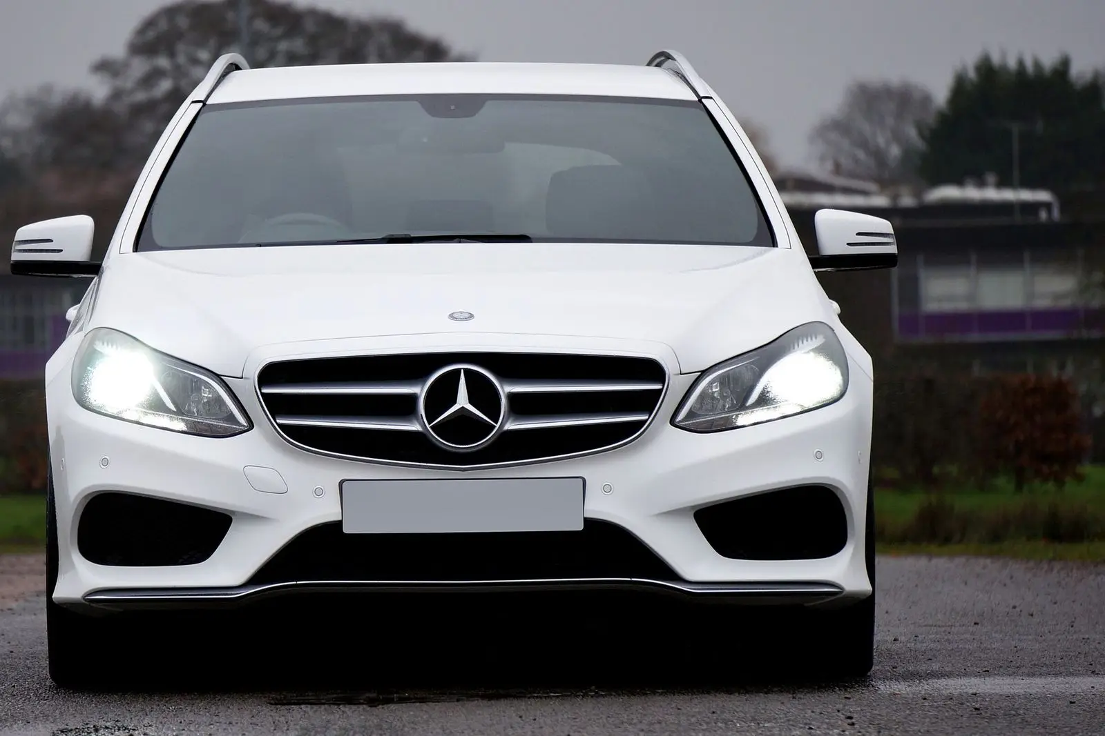 White station wagon with headlights on, front view